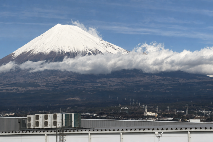 白雲環繞富士山雪峰，山腳可見市區建築