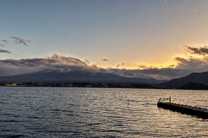 夕陽照亮湖面，富士山隱在雲霧之中