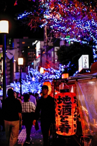 藍色燈飾照亮夜晚街道，兩旁商店招牌閃爍