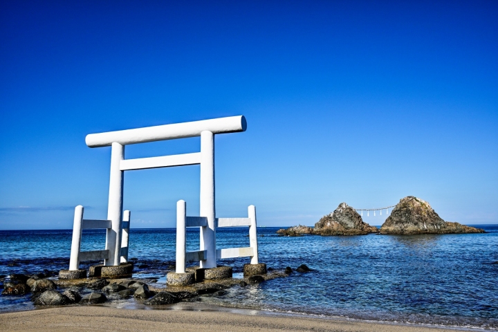 海邊白色鳥居的側影與遠方岩石