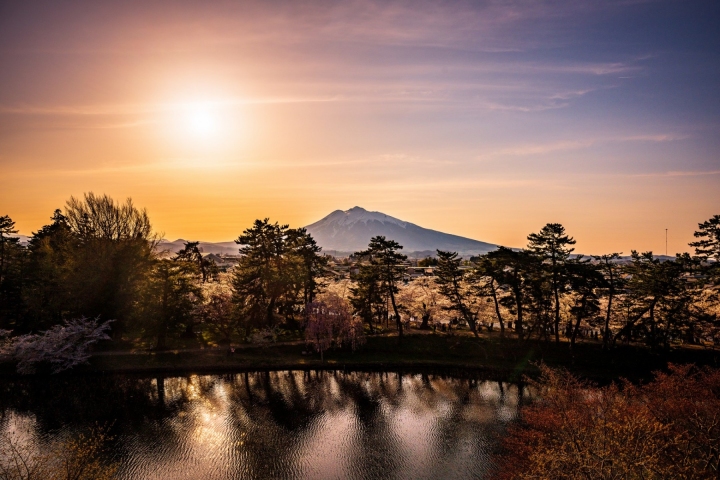 夕陽懸在城樓與遠山上方，護城河泛著金光